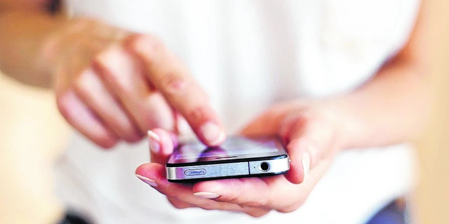 Persona con un celular en la mano enviando un mensaje