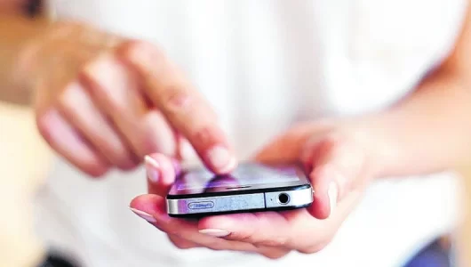 Persona con un celular en la mano enviando un mensaje