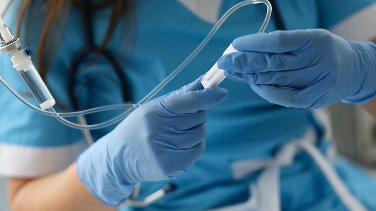 Female nurse hand in blue protective gloves hold dropper